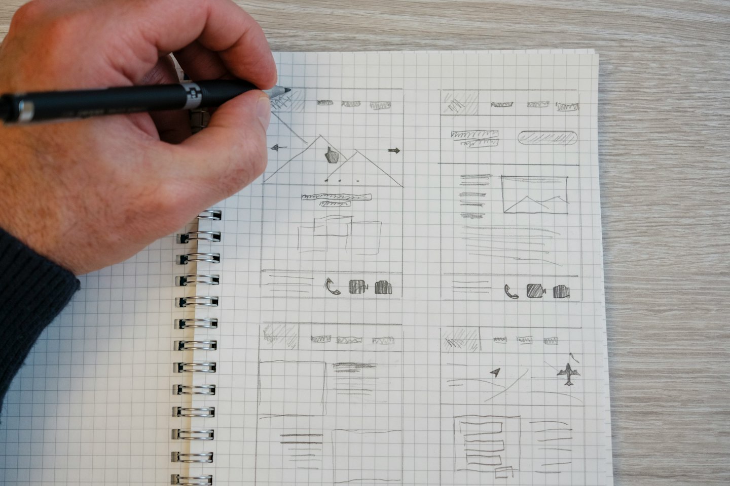 Hand sketching website wireframes on grid paper.